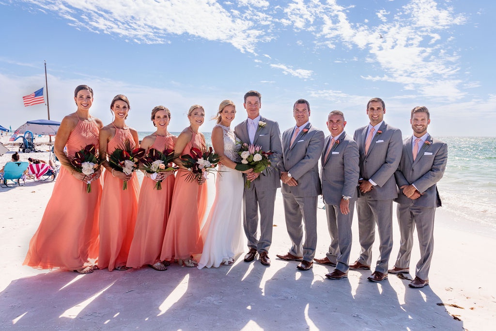 wedding party in peach dresses and gray suits for beach wedding