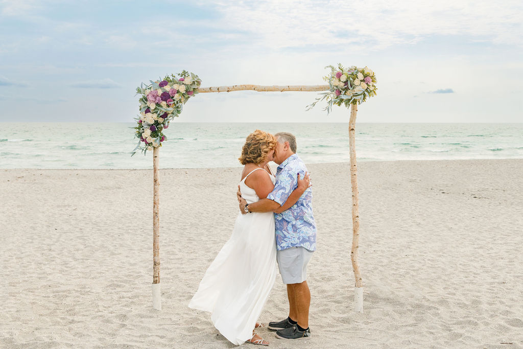 bride and groom under their ceremony arch at Sharkys Beach wedding