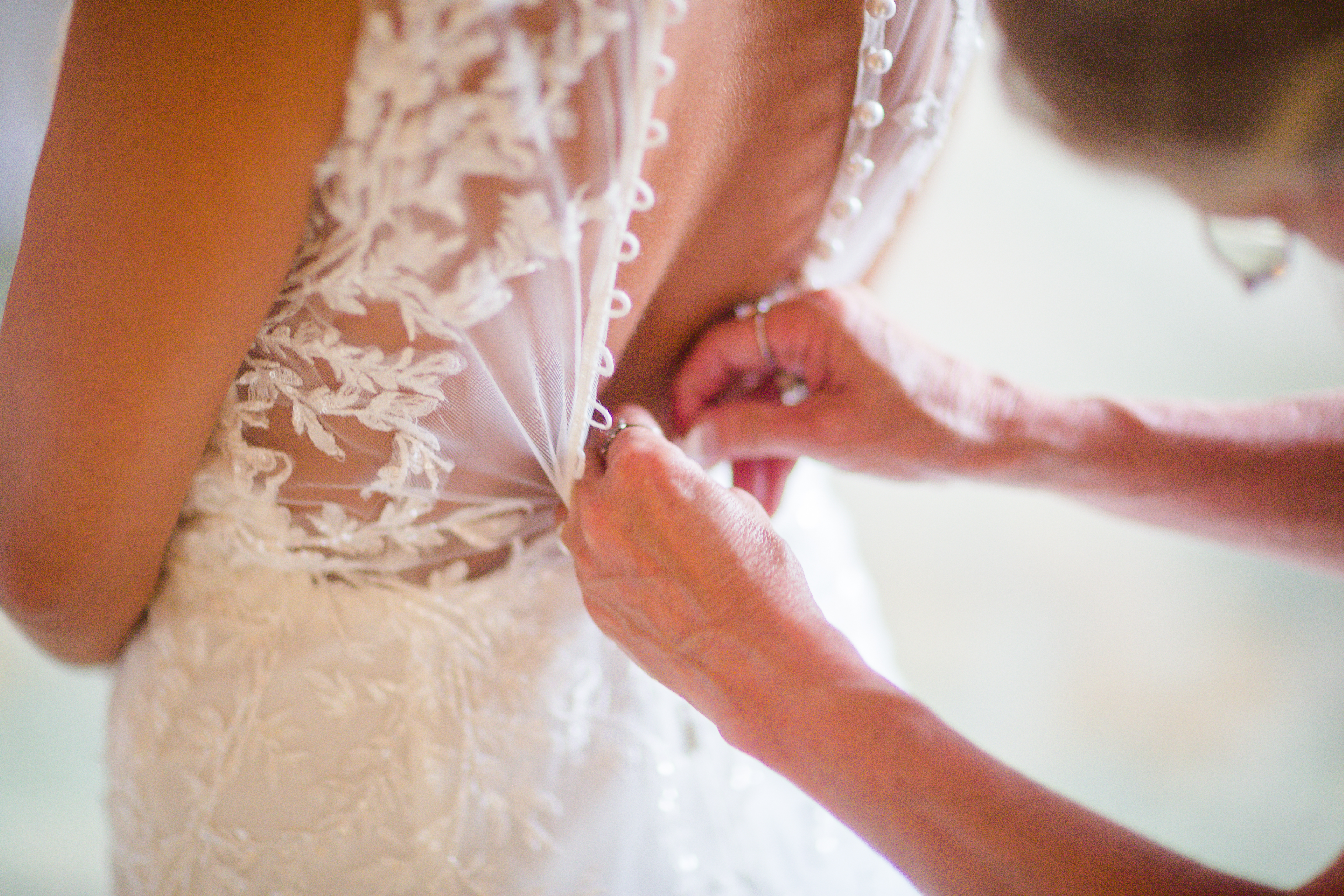 bride's mother helping bride into dress