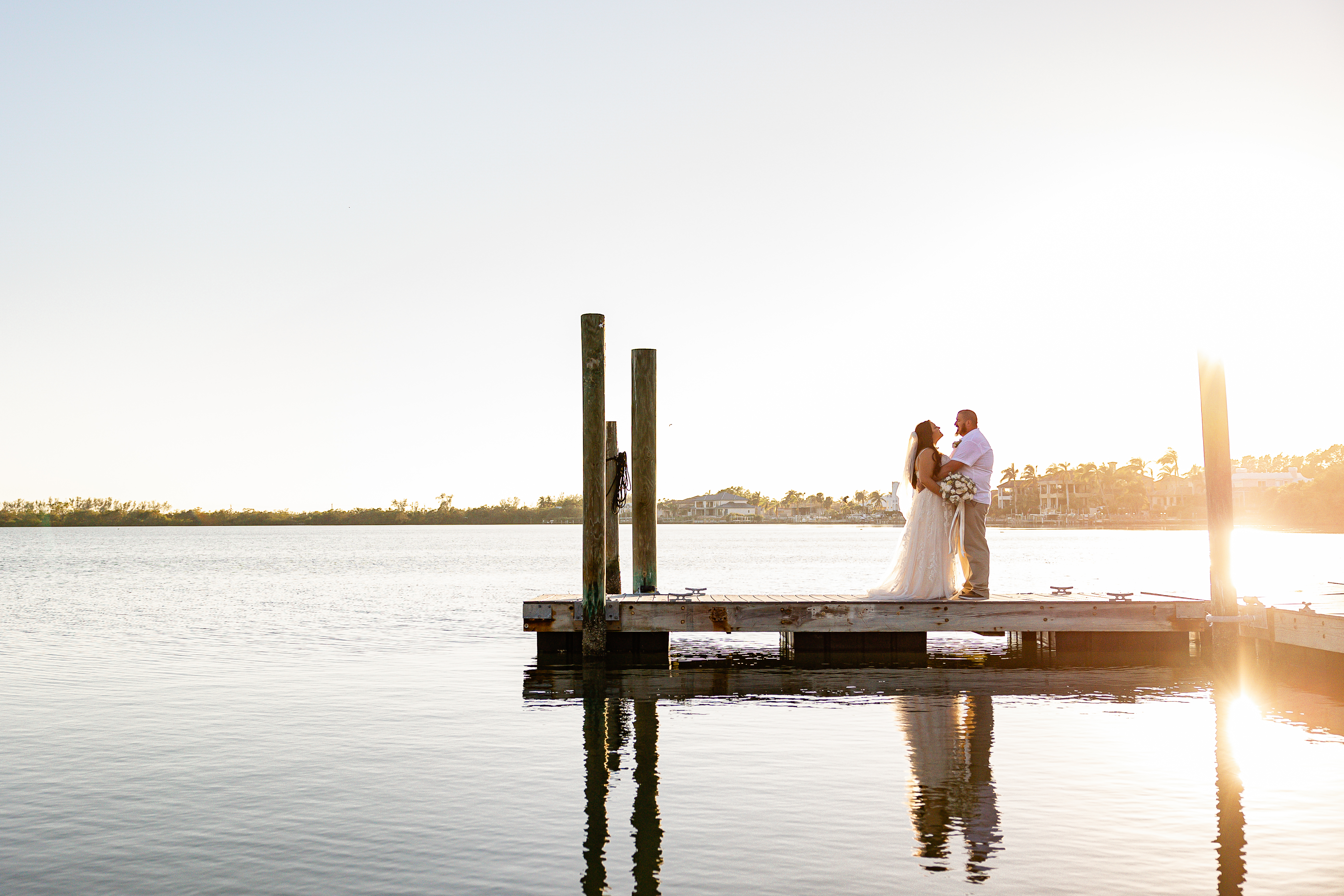 Golden Hour; A couple standing in each-others embraced on a dock as the sun sets.