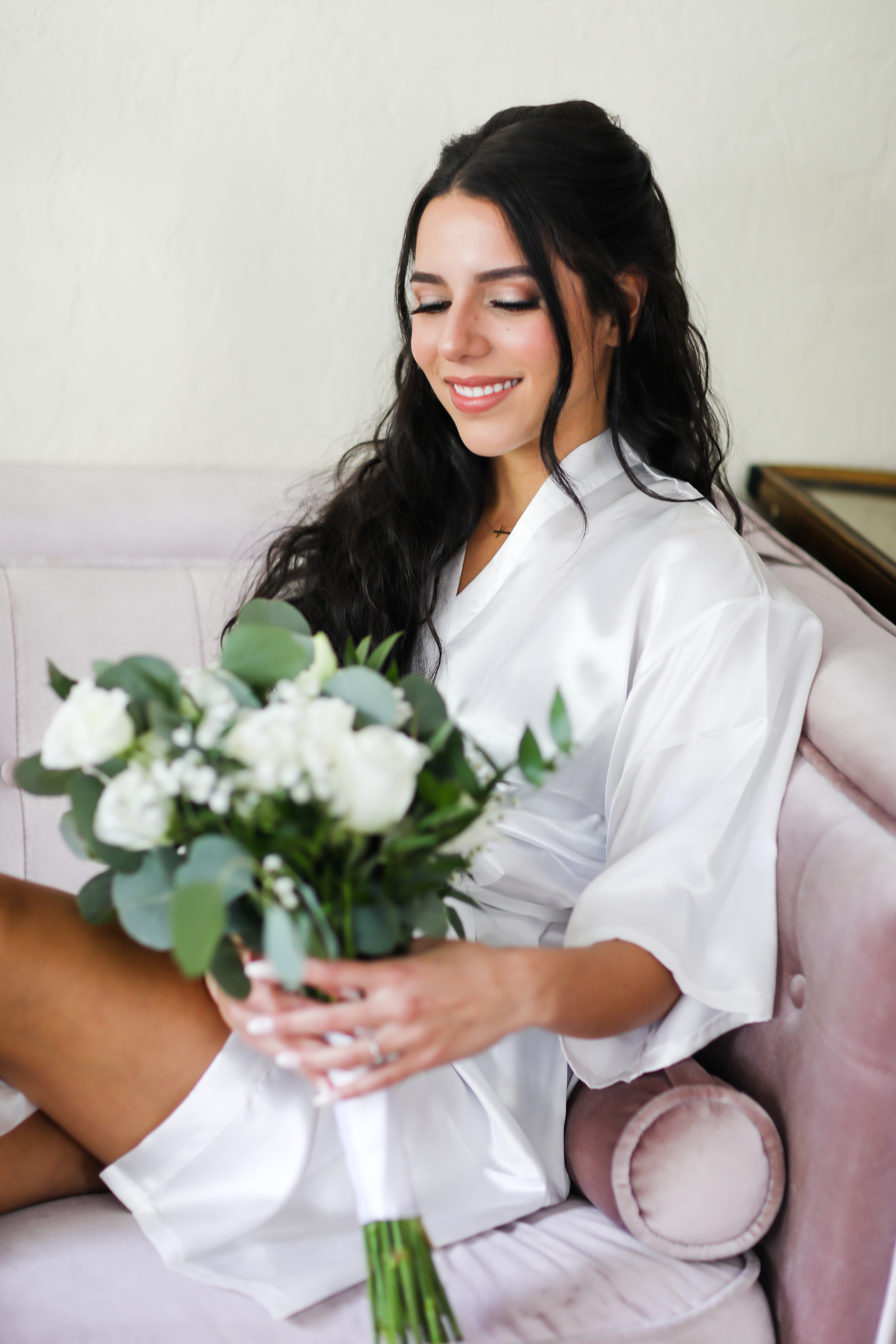 bride in getting ready robe holding her white roses and eucalyptus bouquet 