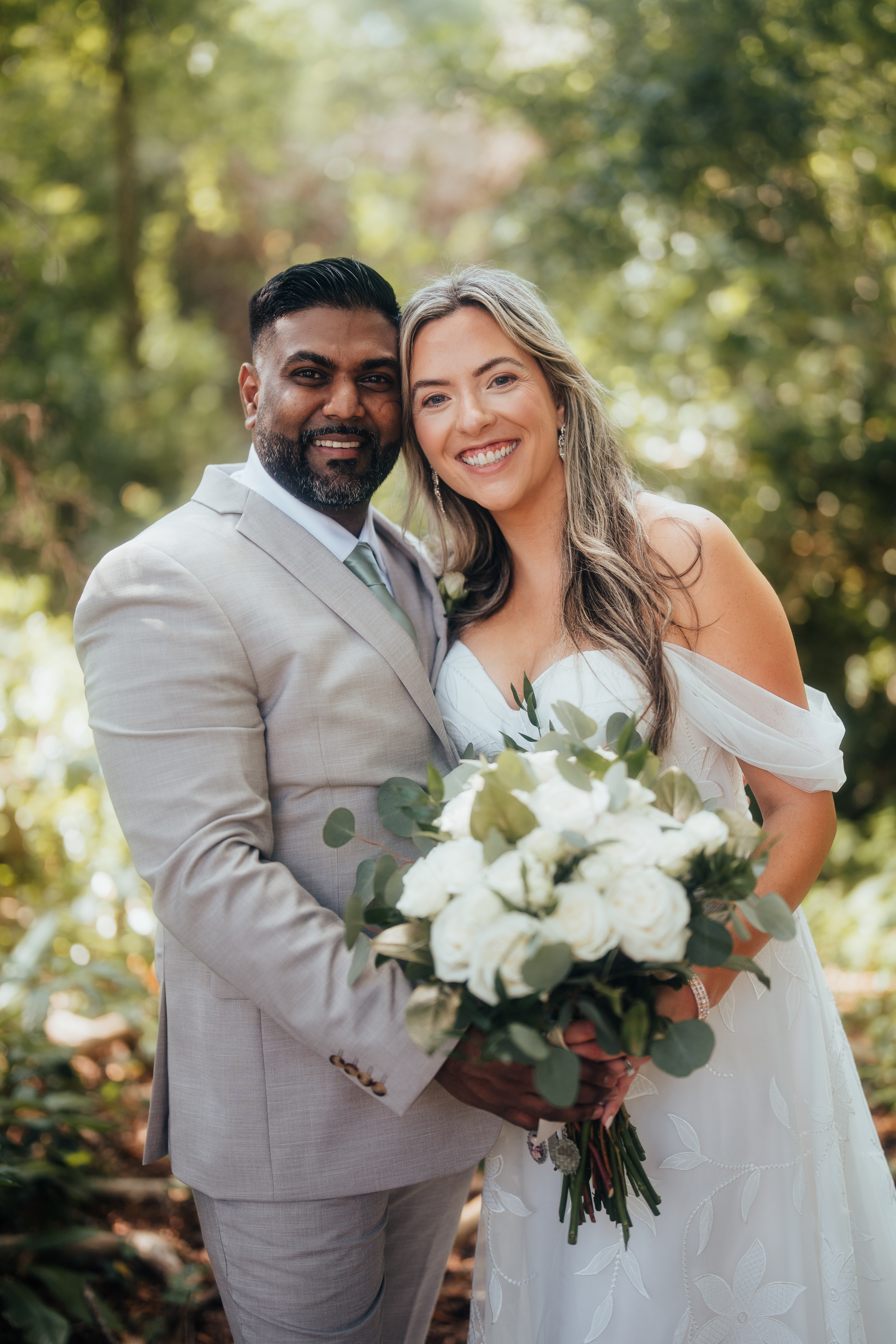 groom in tan suit with sage tie and bride in off shoulder floral gown