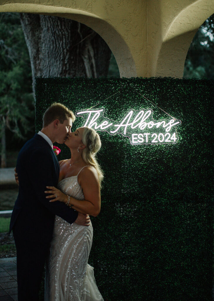 bride and groom with greenery wall