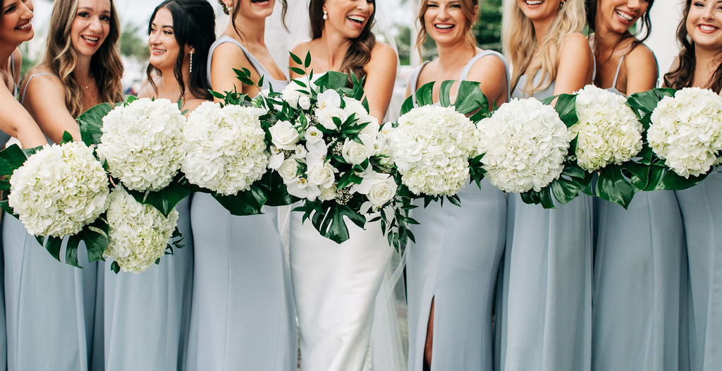 bridesmaids in teal dresses with white floral and palm leave bouquets