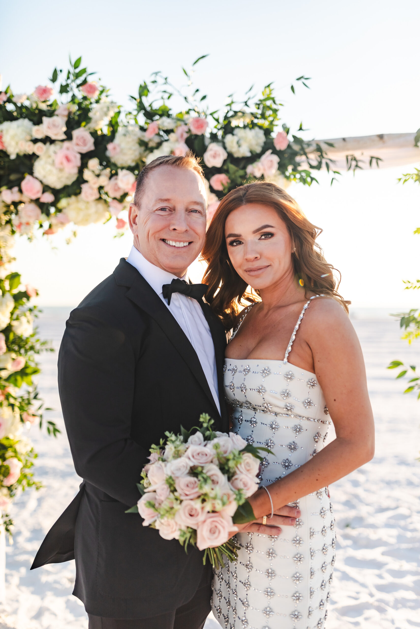 bride in patterned dress and groom in black tux for beach wedding