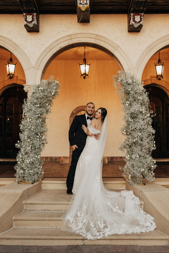 bride and groom under baby's breath wedding ceremony arch