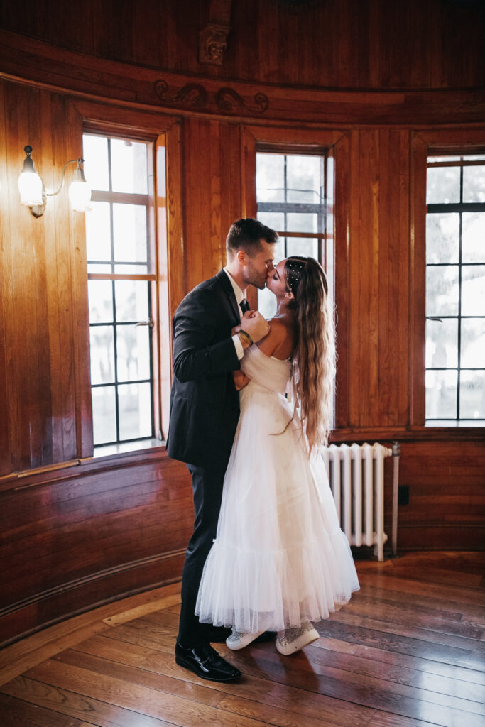 groom in black suit and bride in tulle wedding gown and sneakers