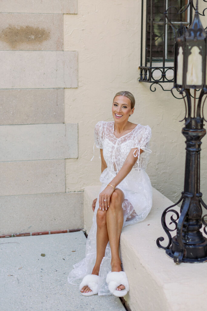 bride in white lace getting ready robe and fluffy slippers