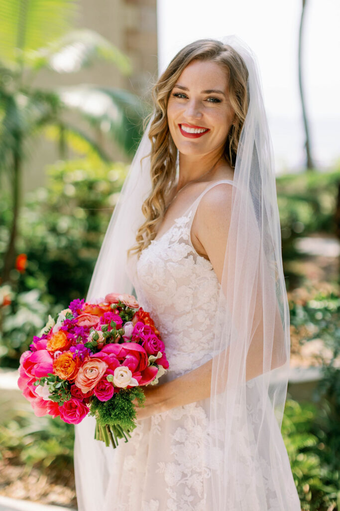 bride in elegant lace wedding gown with bright pink bouquet