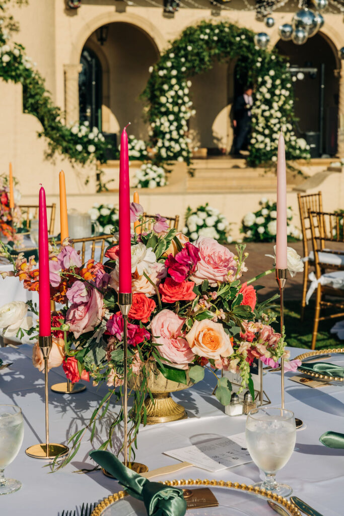 centerpiece with candles, gold accents, and colorful flowers