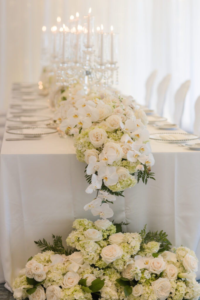 overflowing wedding centerpiece with white florals and candles