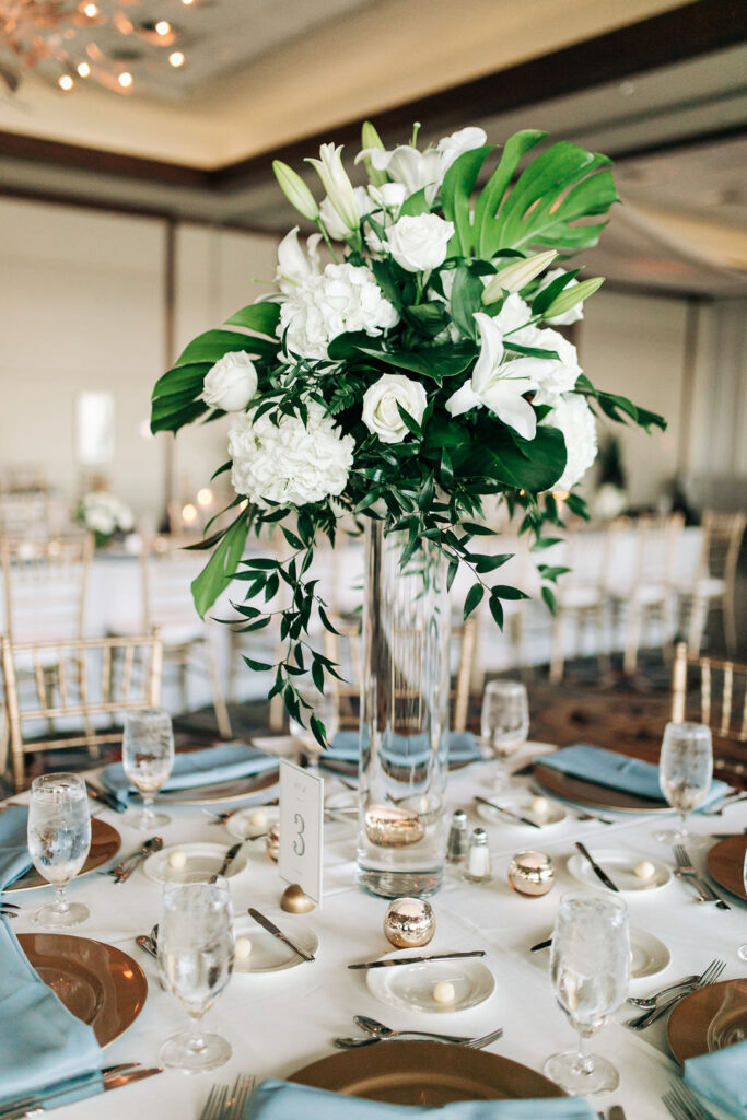 tall wedding centerpieces with white flowers and palm leaves by Precious Moments Events