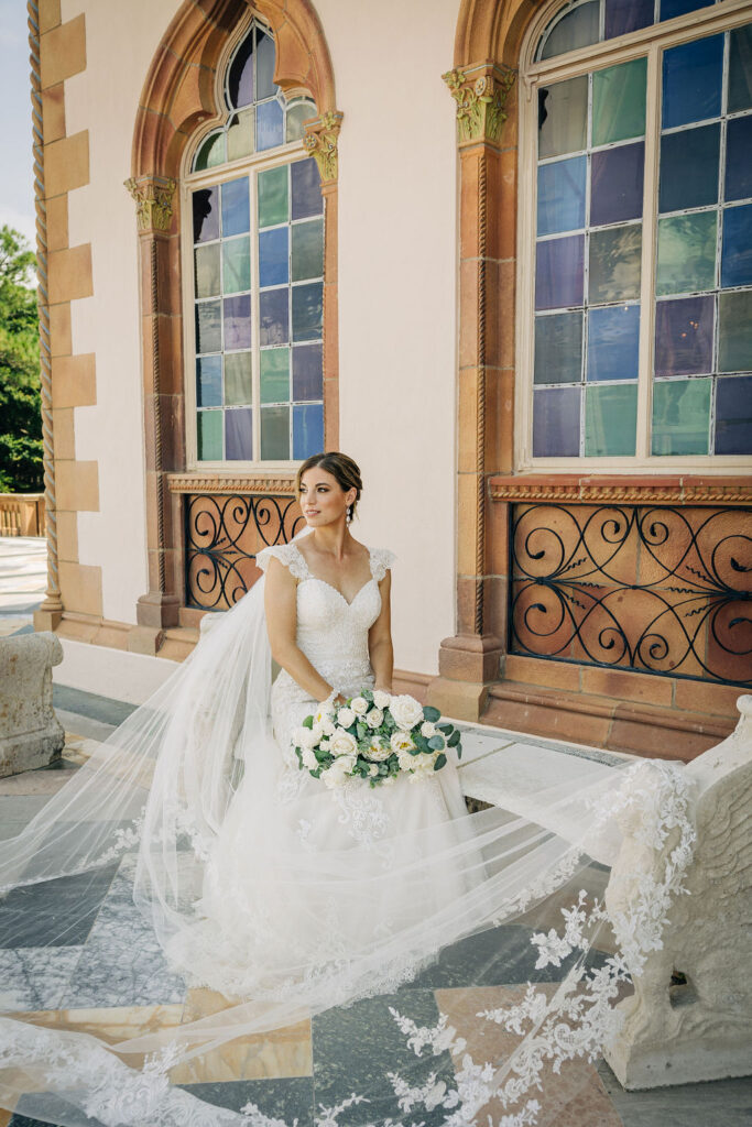 bride with lace lined cathedral veil and white floral bouquet