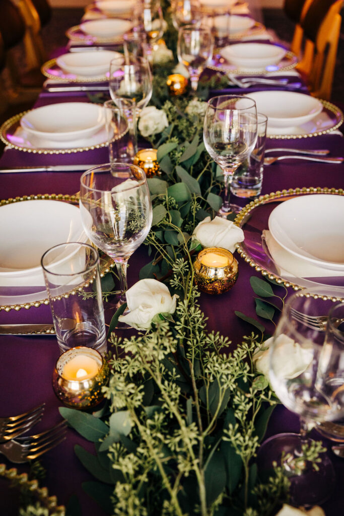 wedding centerpiece with greenery, white roses, and votive candles  