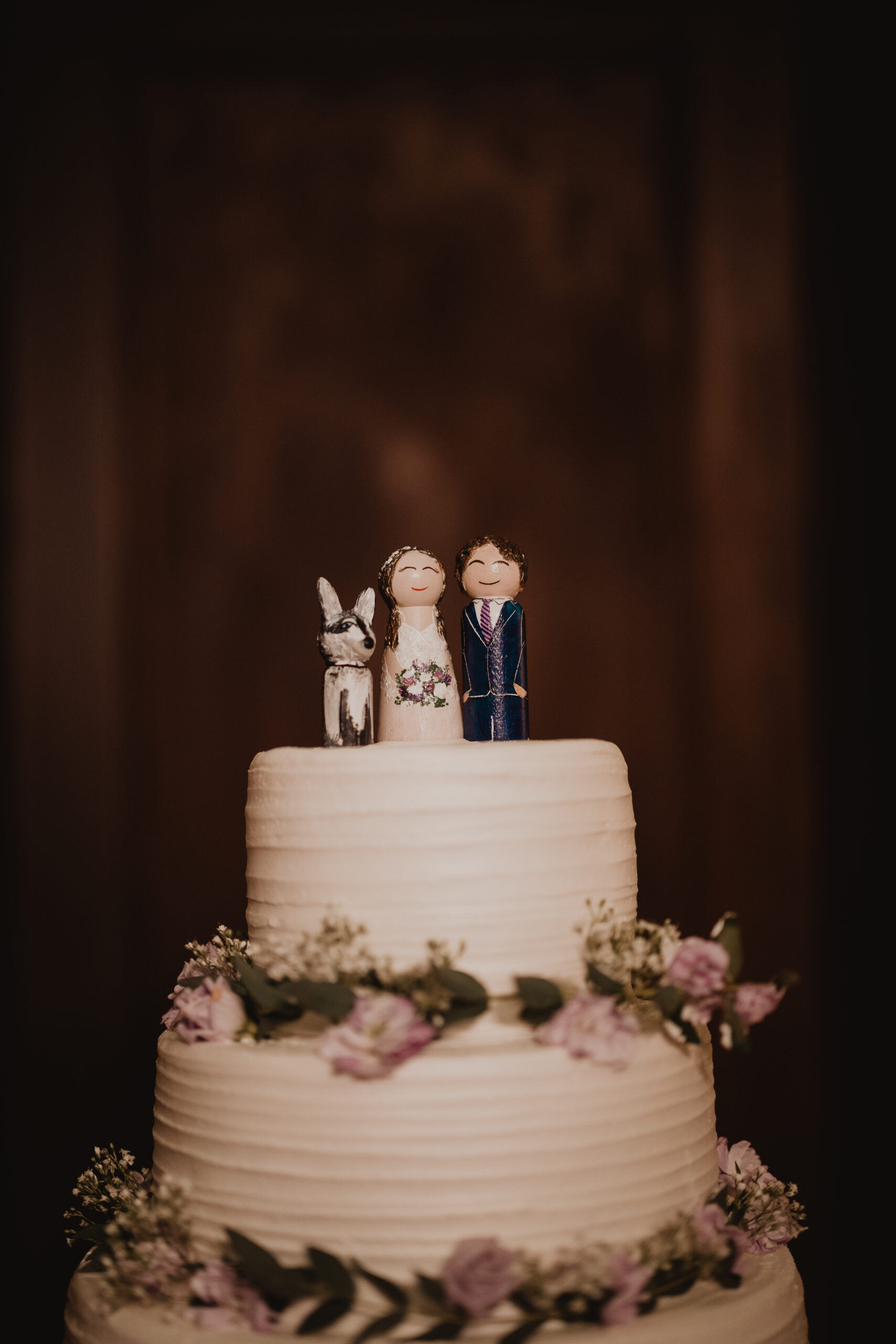 white wedding cake with floral accents and custom cake topper