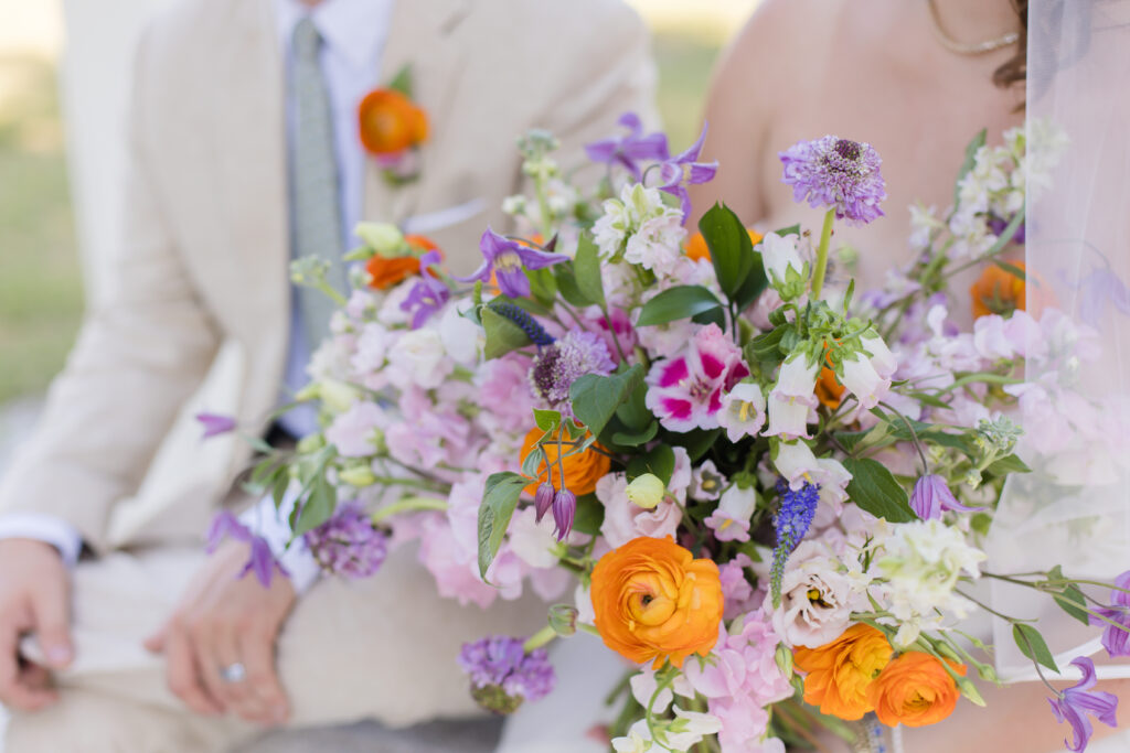 bridal bouquet with orange, purple, and pink flowers