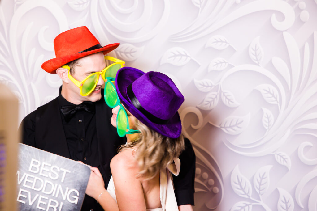 bride and groom in silly hats and glasses for wedding photobooth