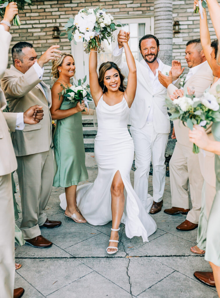 groomsmen in tan suits and bridesmaids in green dresses