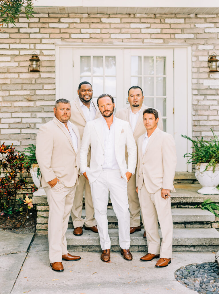 groom in white suit and groomsmen in tan suits