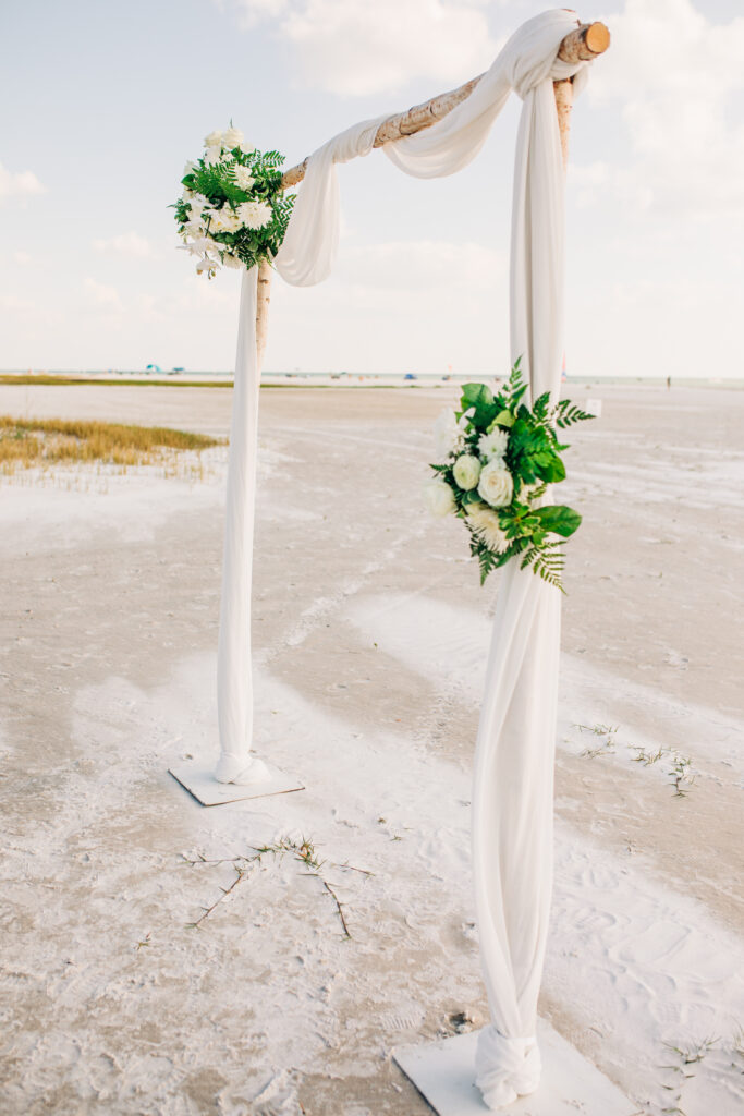 wedding ceremony arch with white linen and white flowers.