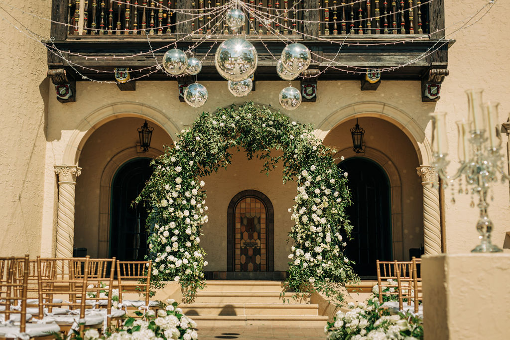 large wedding ceremony arch covered in white roses and greenery