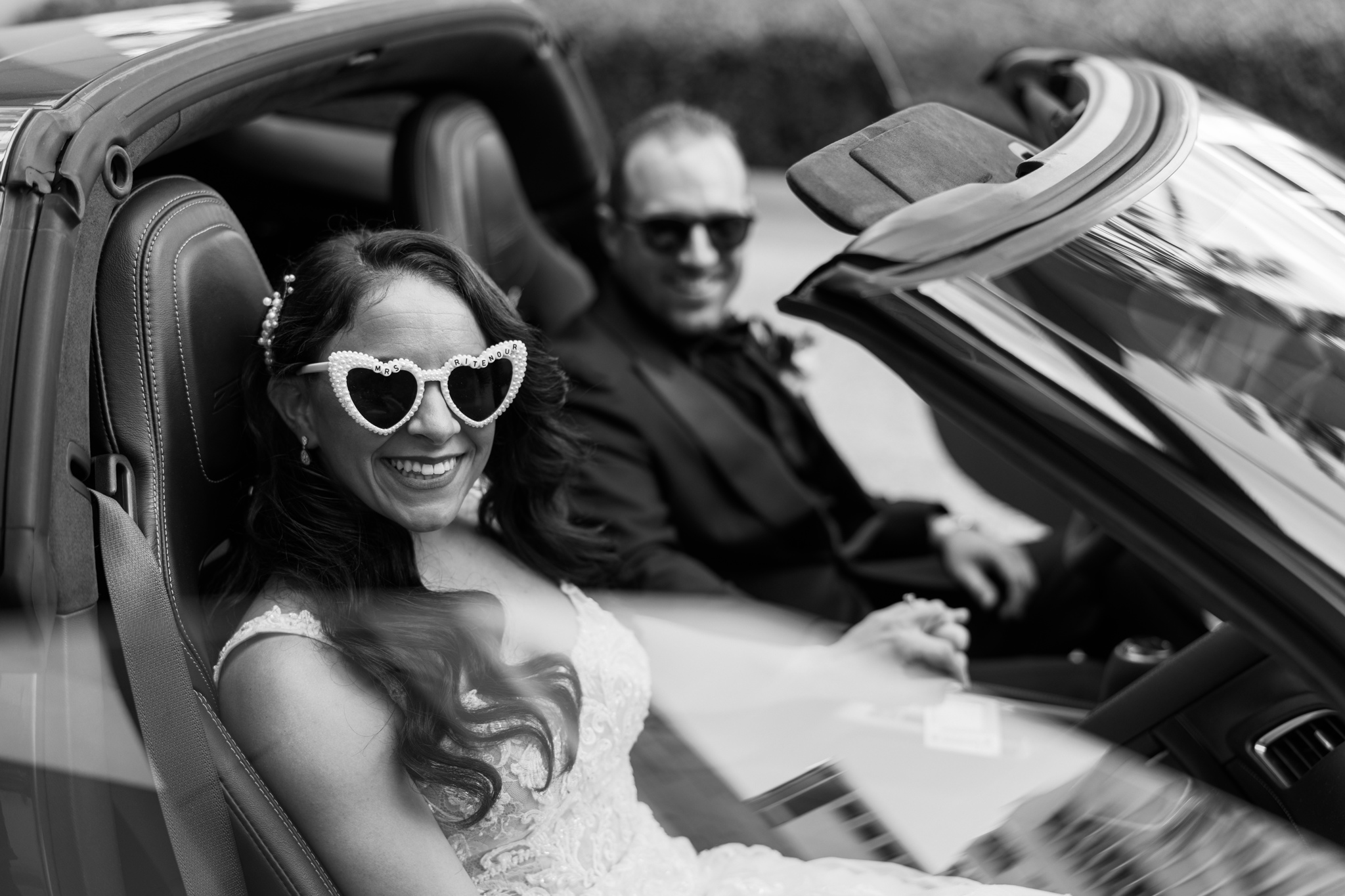 bride and groom exit in car with custom sunglasses