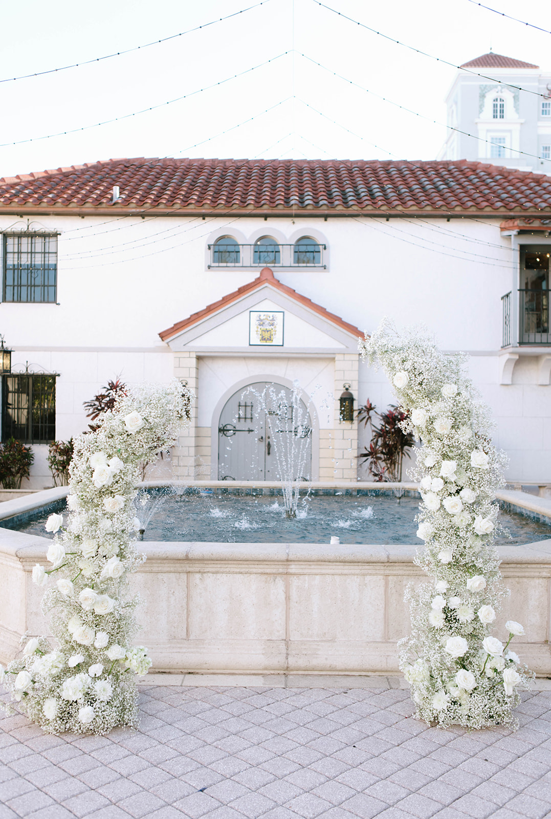 wedding ceremony arch decorated in white florals and baby's breath outside the Bishop Museum of Science