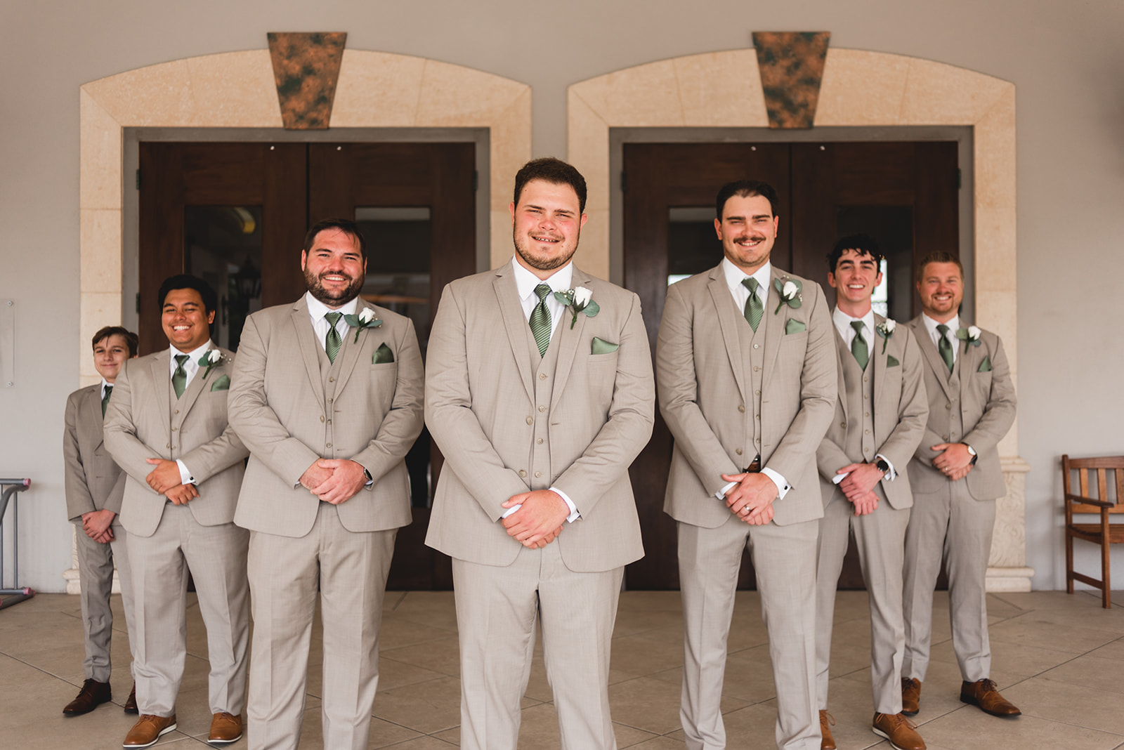 groomsmen in tan suits with green ties