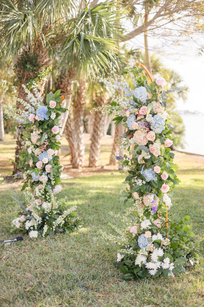 wedding ceremony arch covered in blue, pink, and white flowers